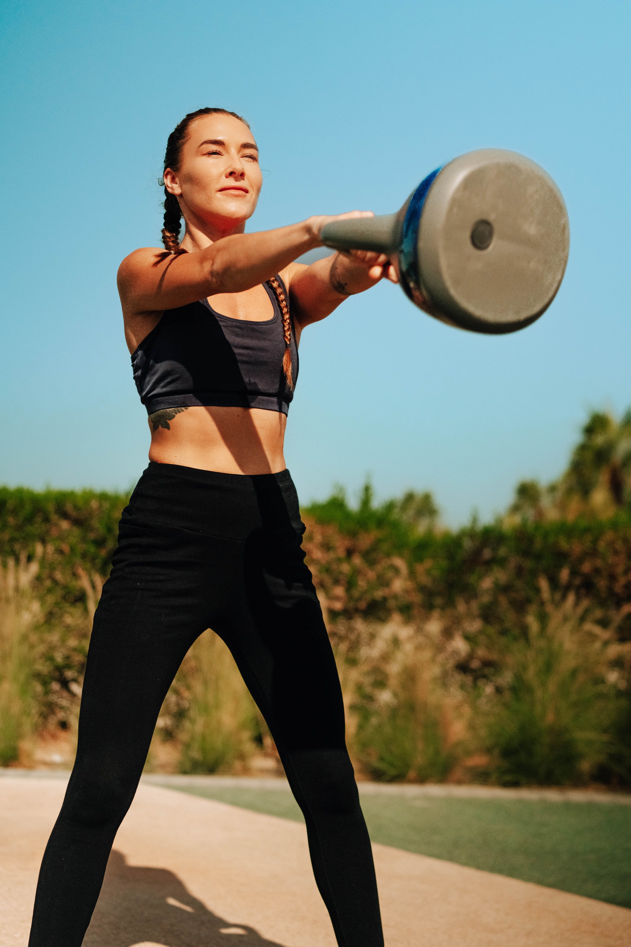 Woman exercising with a weight outdoors on a sunny day in UAE.  Wearing natural , sustainable activewear. perfect for gym warehouse 